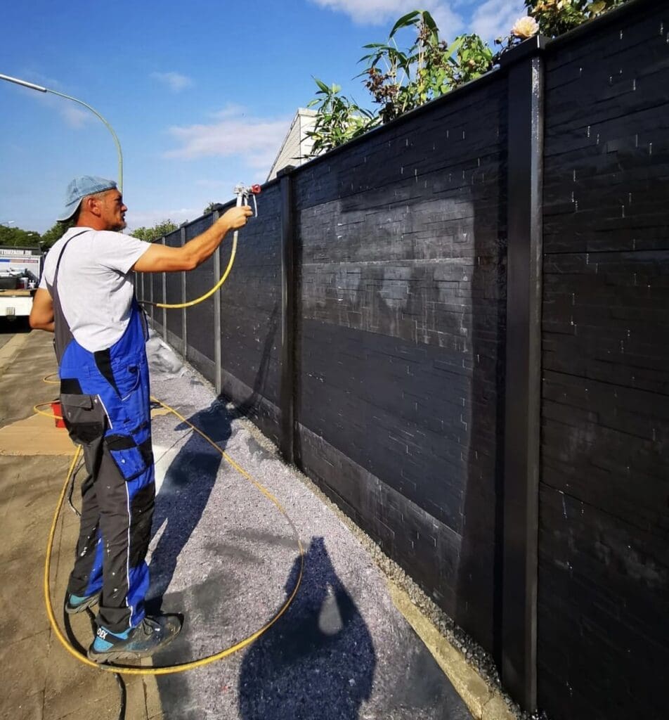 Farbe auf den Betonzaun auftragen